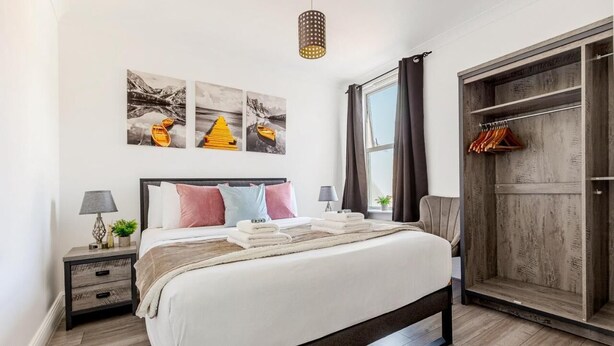 Ein ordentlich eingerichtetes Schlafzimmer mit Bett, Nachttischen, einem Kleiderschrank und Bildern an der Wand.