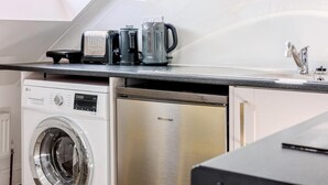 Eine kompakte Küche mit Waschmaschine, Geschirrspüler und Kaffeemaschine auf der Arbeitsfläche.