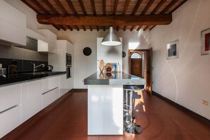 A modern kitchen with white cabinets, a central island, and a hanging pendant light. - Villa Charming on the Hills | Mixed of Authentic and Modern Tuscan Style (Siena)