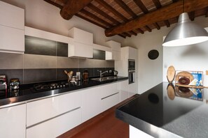 A modern kitchen with white cabinets, a black countertop, and a wooden ceiling.