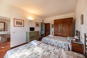 A bedroom with two beds, a dresser, a television, and a wardrobe.