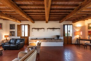 Uma sala de estar ampla com teto de madeira, lareira e mesa de jantar.