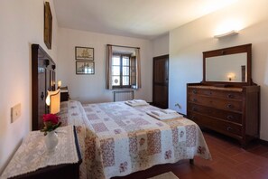 A bedroom with a bed, dresser, mirror, and a window with curtains.