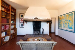 A cozy living room with a fireplace, a bookshelf, and a map on the wall. - Villa Charming on the Hills | Mixed of Authentic and Modern Tuscan Style (Siena)