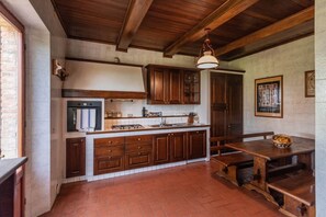 Una cucina rustica con mobili in legno, un piano cottura integrato e una grande isola con posti a sedere.