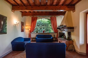 Un accogliente soggiorno con soffitto in legno, un divano, una lampada e un camino.