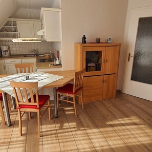 Una cocina compacta con una mesa de comedor, sillas y un mueble de madera.