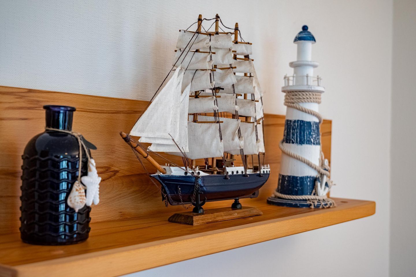 Ein Holzboden mit einem Modellschiff, einem Leuchtturm und einer dekorativen Flasche.