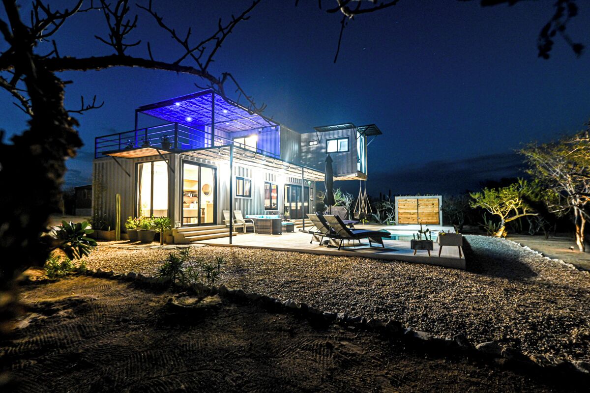 Una casa moderna con fachada de vidrio, mobiliario exterior y piscina.