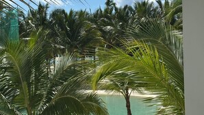 Ein Poolbereich eines Resorts mit Palmen, Liegestühlen und freiem Blick auf den Ozean.