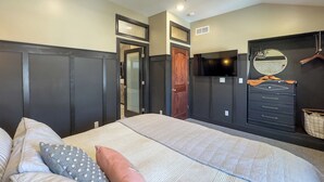 Une chambre à coucher avec un lit, des oreillers, une commode, un téléviseur et une armoire.