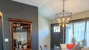 Un coin repas comprenant une table en verre, des chaises, un meuble en bois et un luminaire suspendu.