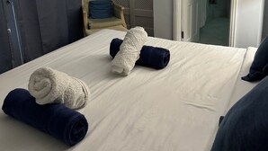 Ein Hotelzimmer mit einem Bett, einem Sessel und einem durchgegangenen Tür sichtbar liegenden Badezimmer.