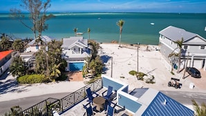 A beachfront property with a swimming pool, multiple houses, and a view of the ocean. - Salt Dreams: 1 Block to Beach! Pool, Spa, Games, Rooftop Deck by Anna Maria Life Vacation Rentals (Anna Maria)