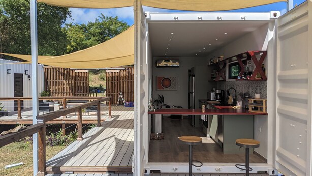 Cocina y comedor integrados y compactos con una terraza de madera y un toldo.