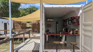 A compact, open-plan kitchen and dining area with a wooden deck and a canopy.