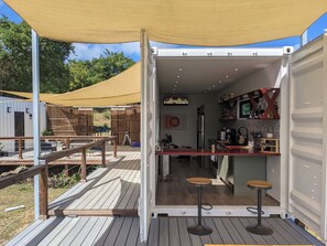 A compact, open-plan kitchen and dining area with a wooden deck and a canopy.