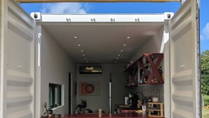 Un espacio pequeño y abierto con kitchenette, dos taburetes y una zona de comedor.