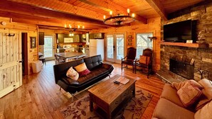A spacious log cabin interior with a living room, kitchen, and dining area.