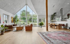 A spacious living area with large windows, a dining area, and a kitchen. - Cozy home in Aarup with WiFi (Aarup)