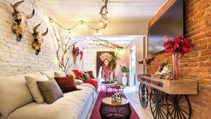 Un salon chaleureux avec un canapé blanc, une moquette rouge, un chariot en bois et des crânes décoratifs.
