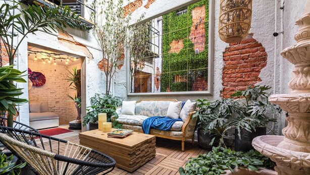 Un patio intérieur accueillant, avec un canapé, des fauteuils et une table basse en bois.