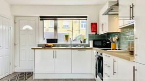 Eine moderne Küche mit weißen Schränken, einer Holz Arbeitsplatte und einem Fenster mit Blick auf Gebäude.