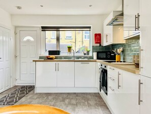 Una cocina moderna con armarios blancos, una encimera de madera y una ventana con vistas a edificios.