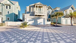 A residential area with a two-story house featuring a balcony, a garage, and a paved driveway. - Sea View, Shared Resort Style Pools, Boardwalk to the Beach, Golf Cart Access (Port Aransas)