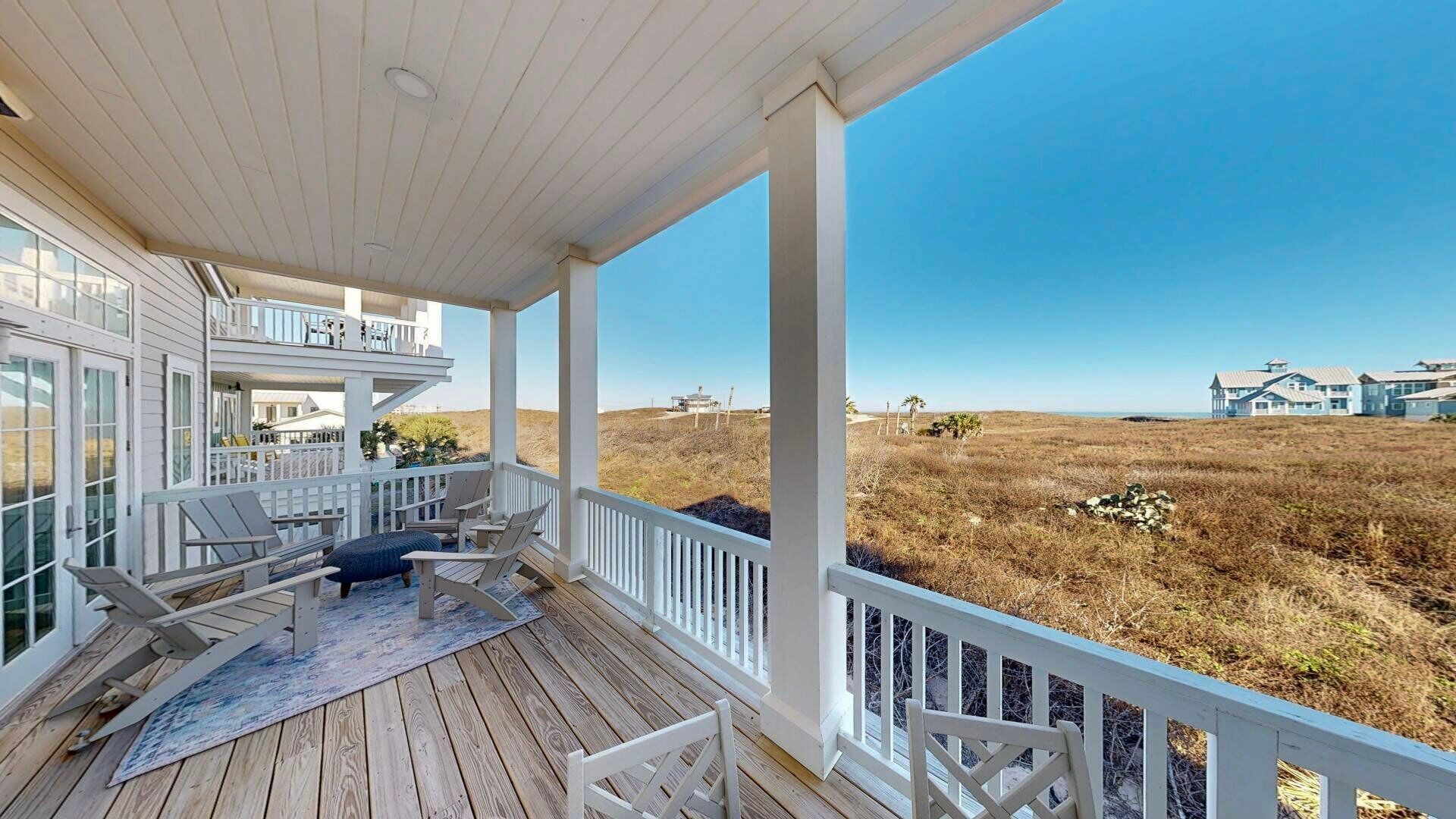 A wooden deck with outdoor seating and a view of a coastal landscape.