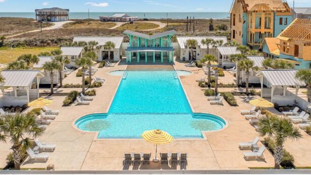 A resort with a central swimming pool, lounge chairs, and a view of the ocean. - Sea View, Shared Resort Style Pools, Boardwalk to the Beach, Golf Cart Access (Port Aransas)