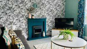A living room with a fireplace, sofa, television, and decorative plants. - Halifax Centre → 8 min | Dogs OK | 50”TV | Parking (Halifax)
