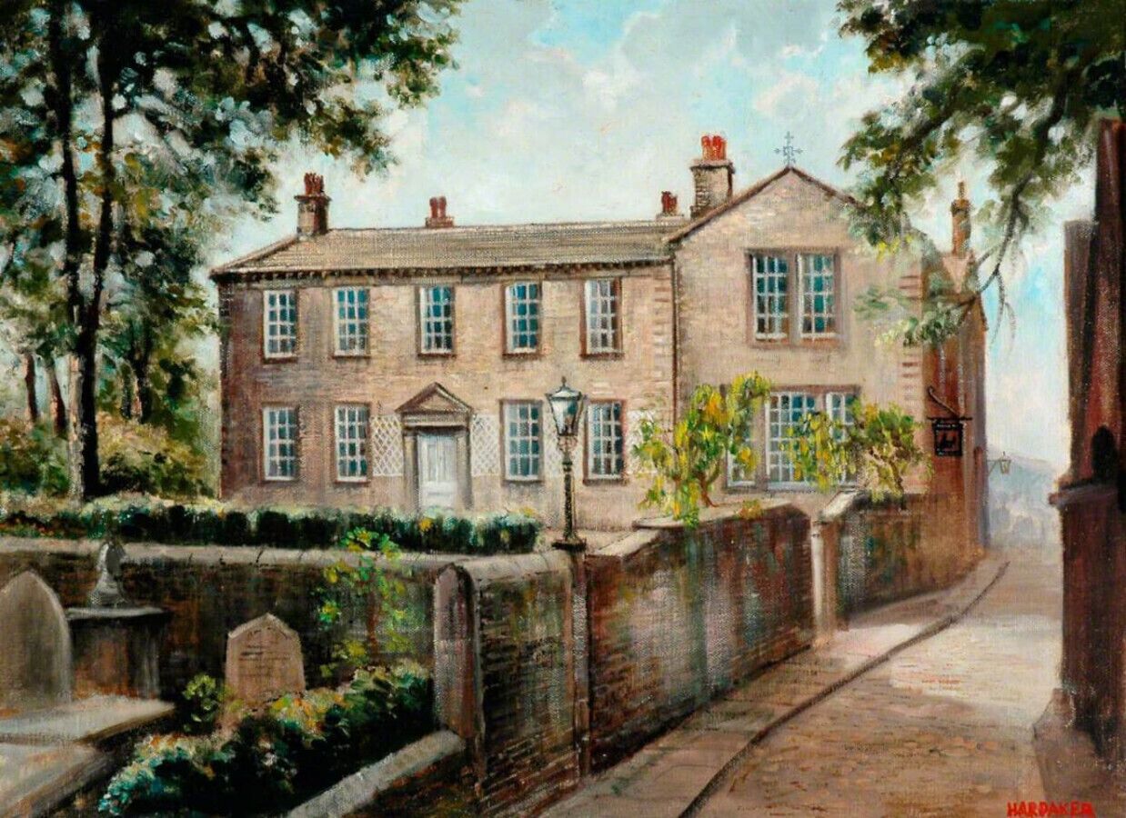 A two-story brick building with a central entrance, a small garden area, and a paved pathway leading to the entrance.