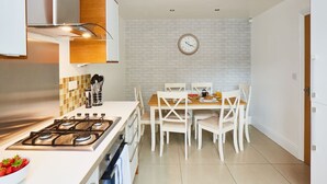 A modern kitchen with a gas stove, white cabinets, and a dining area with white chairs. - Halifax Centre → 8 min | Dogs OK | 50”TV | Parking (Halifax)