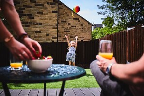 A child playing with a balloon in a backyard with a brick wall and wooden fence.