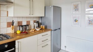 Een moderne keuken met een roestvrijstalen koelkast, een houten aanrechtblad en een betegelde spatwand.