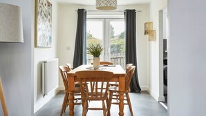 A dining area with a wooden table and chairs, a potted plant, and a pendant light. - Halifax+Piece Hall 4 min| Parking | Pets OK|Garden (Halifax)