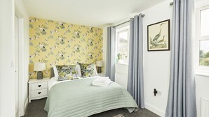 A bedroom with a bed, nightstands, a lamp, a window with curtains, and a wall with a bird pattern. - Halifax+Piece Hall 4 min| Parking | Pets OK|Garden (Halifax)
