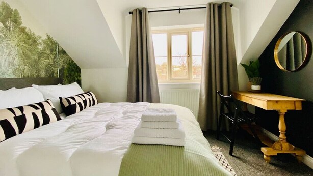 Une chambre à coucher avec un lit, un bureau et une fenêtre avec des rideaux.