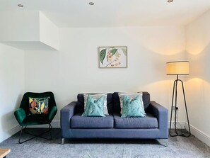 A living room with a grey sofa, a green armchair, and a floor lamp.