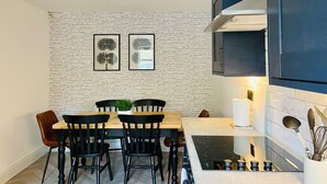 Une cuisine moderne avec un mur en briques, une table à manger avec des chaises et une cuisinière encastrée.