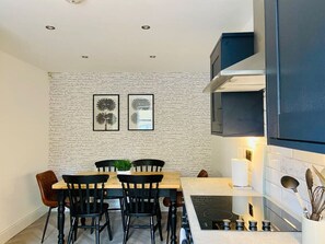 Et moderne køkken med en murstensvæg, et spisebord med stole og en indbygget komfur.