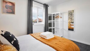 Une chambre d’hôtel avec un lit, une armoire et une fenêtre avec des rideaux.