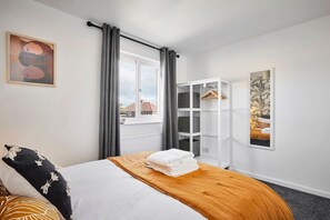 Une chambre d’hôtel avec un lit, une armoire et une fenêtre avec des rideaux.