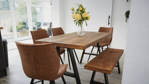 Un coin repas avec une table en bois, six chaises et un vase rempli de fleurs jaunes.