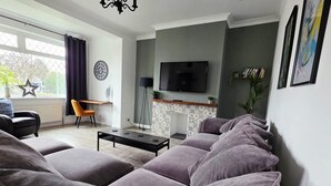 Un salon moderne comprenant un canapé, une table basse, un téléviseur et une cheminée.