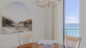 Comedor con vista a la playa, una araña y un cuadro de la playa.