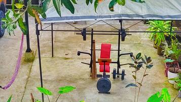Un espacio al aire libre techado con un sistema de poleas, plantas en macetas y suelo de hormigón.
