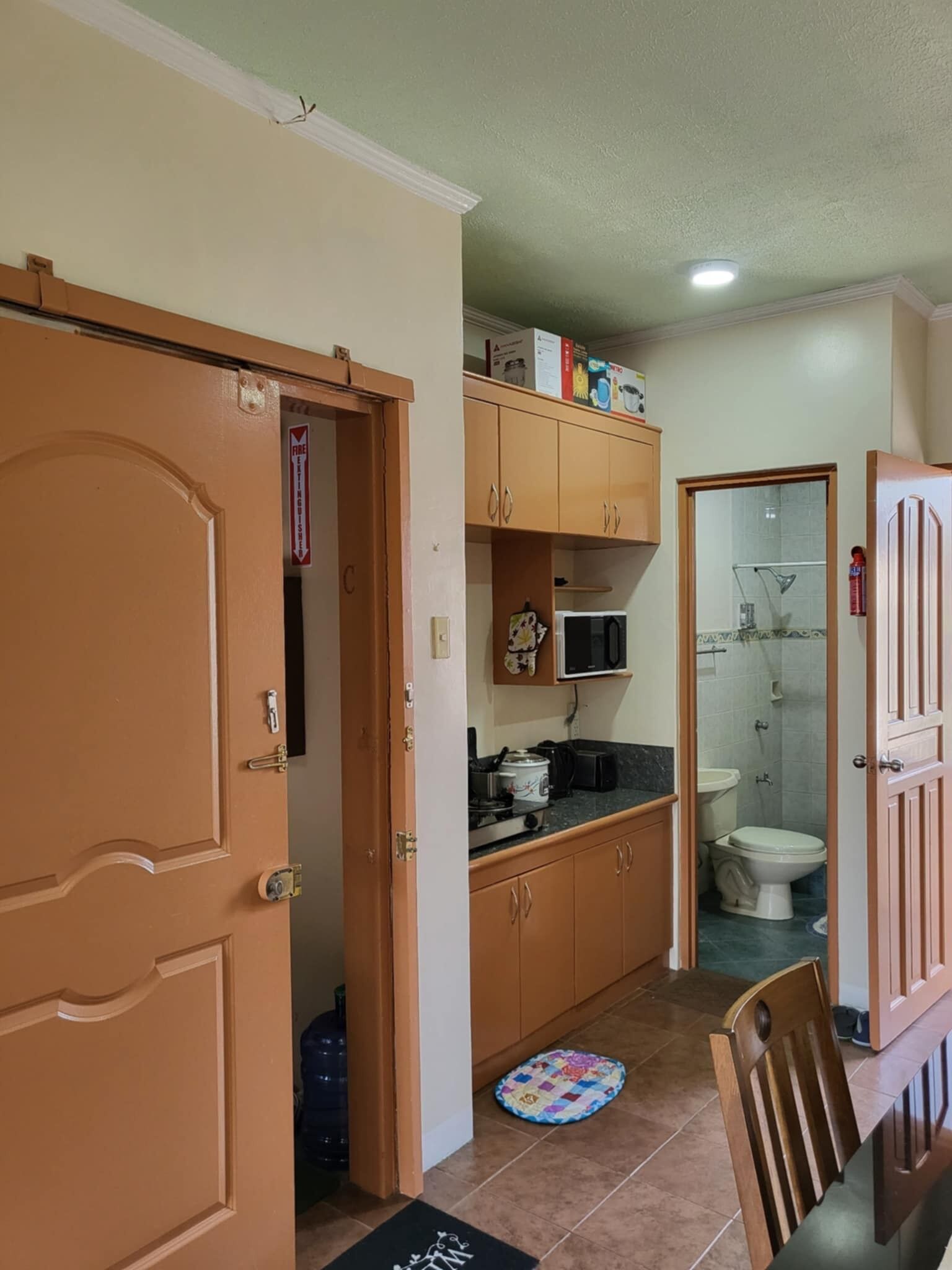 Een kleine keuken met houten kastjes, een magnetron en een spoelbak.