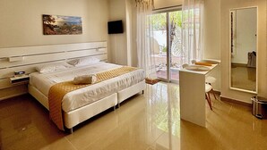 A hotel room with a bed, a TV, a bathroom with a mirror, and a view of the outdoors. - Palapa Suite # 8, walk to Eagle Beach (Eagle)